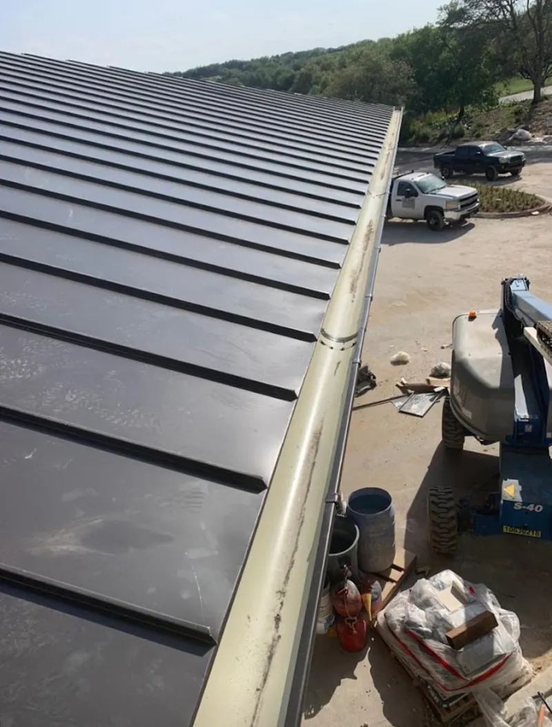 Standing seam panel and gutter detail on a metal roofing jobsite in Posen